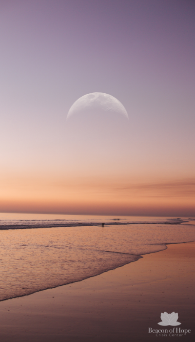 Moon in the sky over a beach during sunset