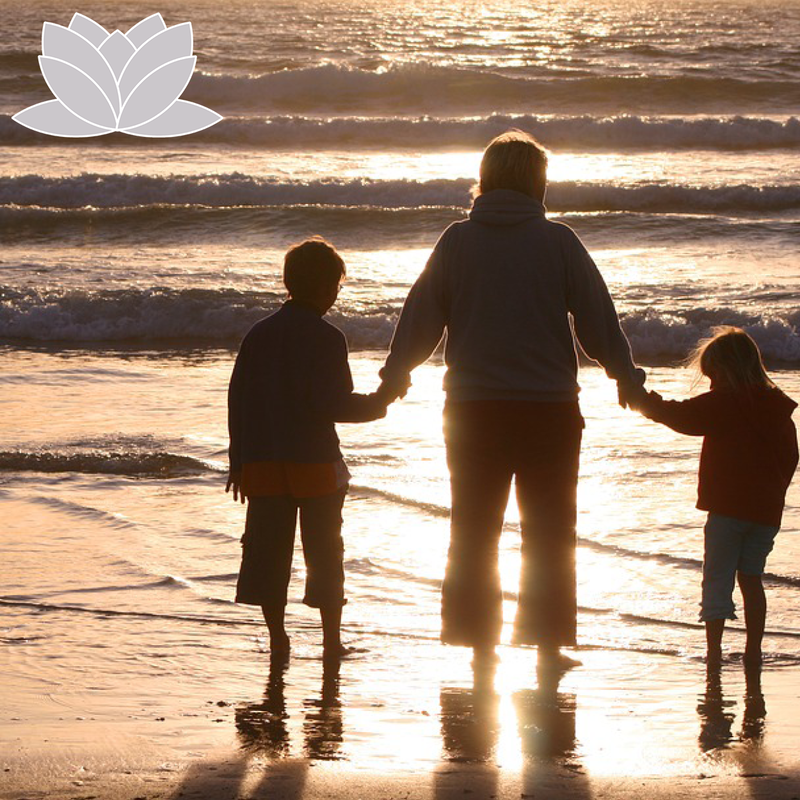 Family holding hands looking out at the ocean.