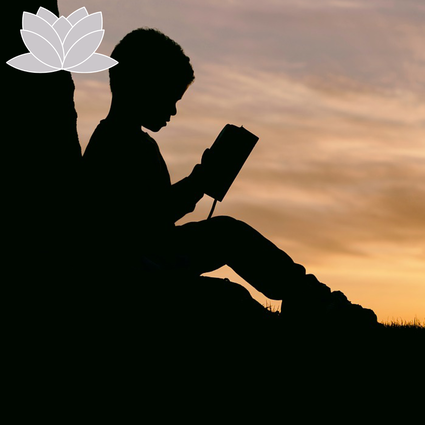 Boy sitting with his back against a tree reading.